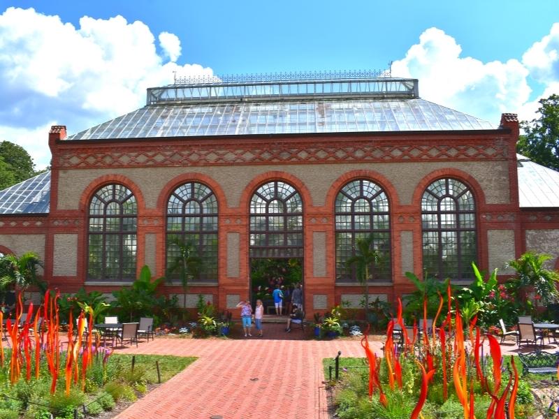 The large stucco and orange brick building with a glass roof houses the Biltmore Conservatory