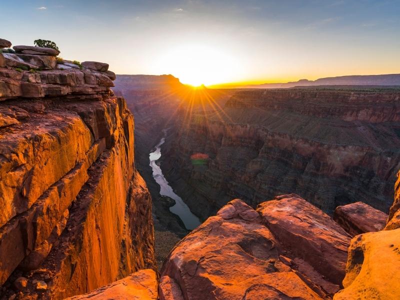 The Grand Canyon lies in dark shade as the rim starts to glow orange as the sun rises over the north rim