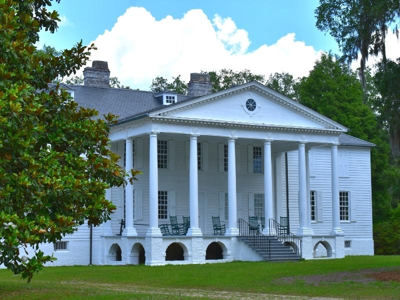 White columned portico of the Hampton Plantation main house under a blue sky and surrounded by green trees