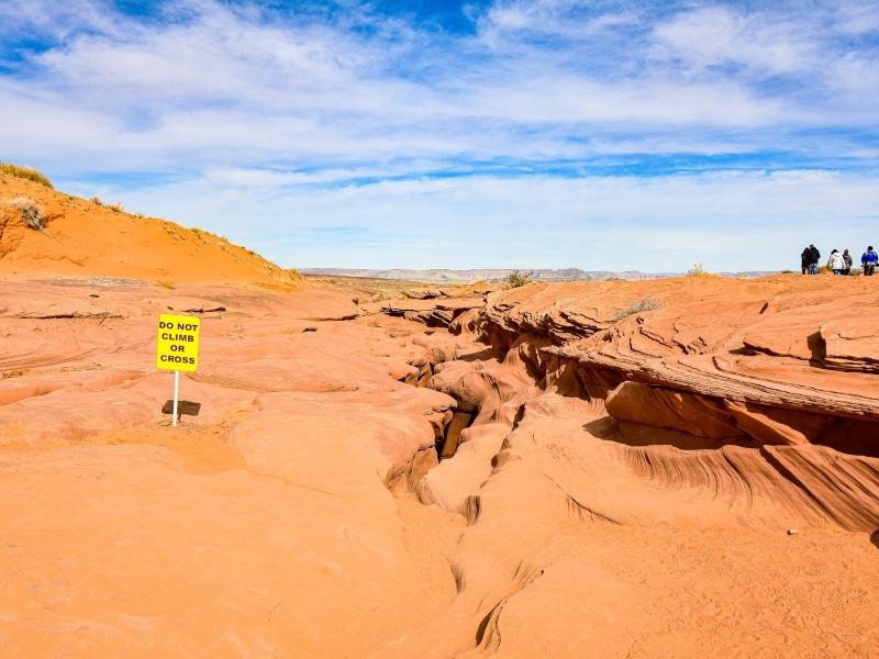 Lower Antelope Canyon tours exit from the top crevice, an entirely orange landscape under a blue and white sky