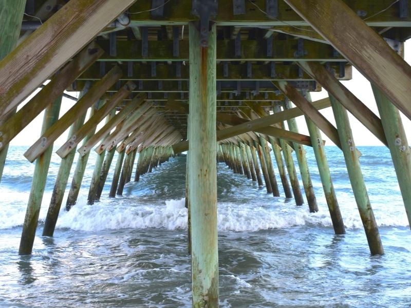 Symmetrical photo of the wooden pier pilings in the surf at Myrtle Beach State Park