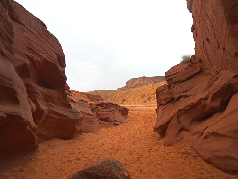 The exit of Upper Antelope Canyon is a wide sandy path between tall red sandstone cliffs