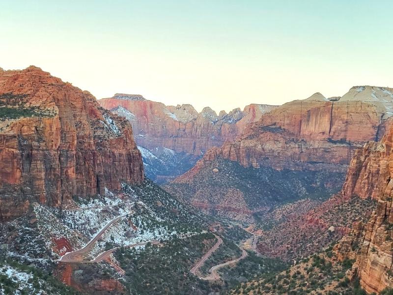 Zion Canyon glows orange at twilight with a bit of snow accenting the greenery