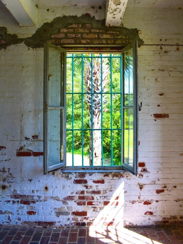 The master bedroom window at Atalaya Castle looks out on a palm tree and greenery