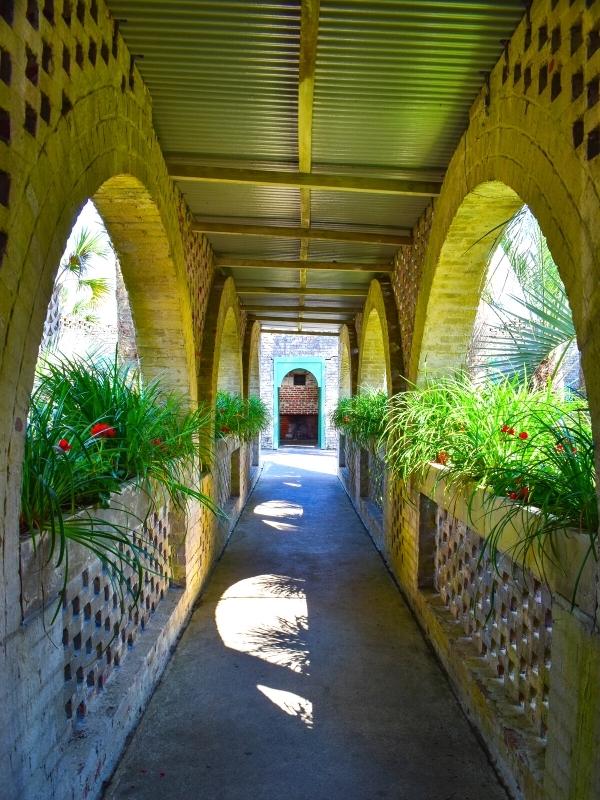 The shady breezeway of Atalaya Castle is adorned with flower boxes that reflect the bright courtyard at Atalaya Castle