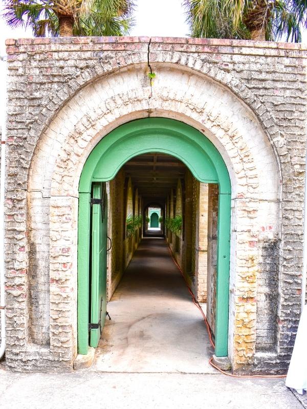 The gray stone and green wooden door entry to Atalaya Castle, looking down the breezeway, at Huntington Beach State Park