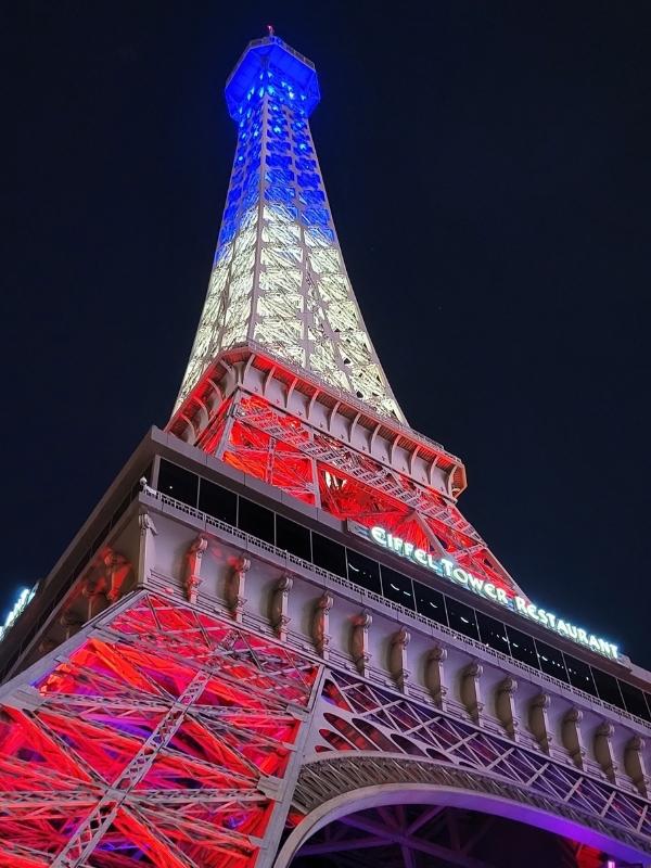 The Eiffel Tower at Paris Las Vegas is lit up in red, white, and blue lights against a black night sky