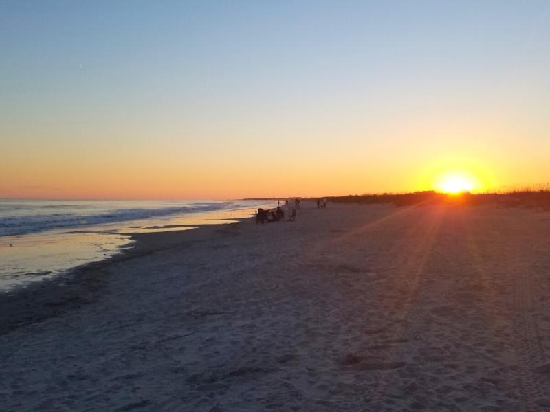 An orange sunset darkens Kiawah Island beach while reflecting off the waves of the Atlantic Ocean