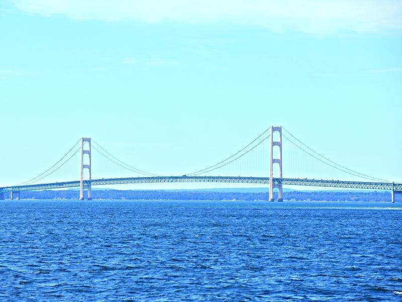 The Mighty Mackinac Suspension Bridge in the distance over the blue waters of the Straits of Mackinac