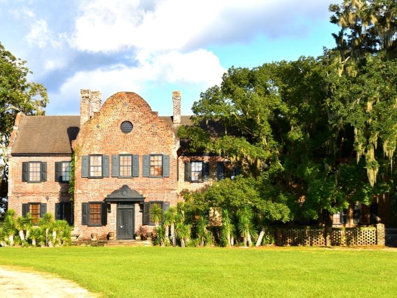 A brick two-story plantation house at Middleton Plantation with live oak trees obscuring the right half