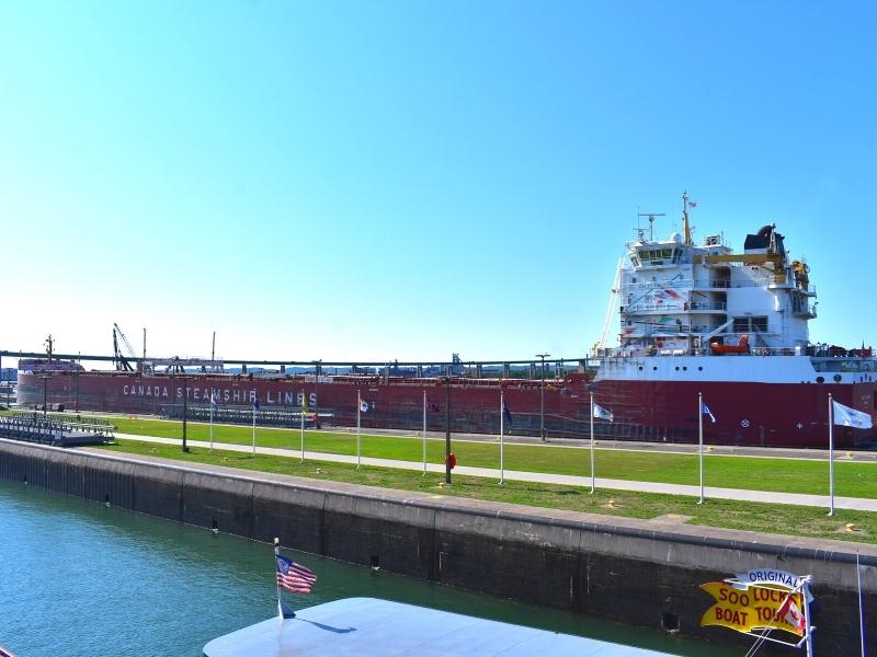 A large freighter ship enters the largest Soo Lock on a clear sunny day