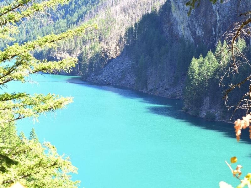 Powder teal blue waters of the Skagit River abut a mountainside in shade