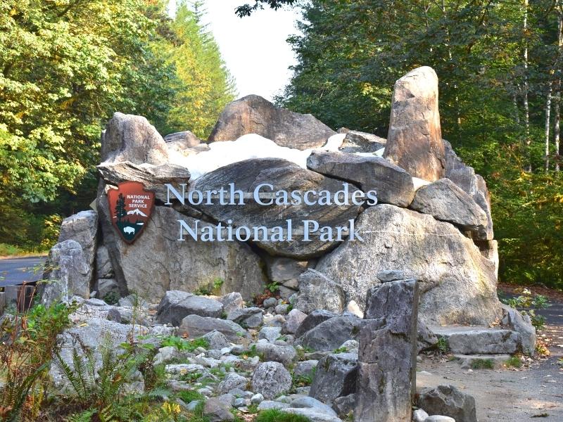 The North Cascades National Park east entrance sign is stone and faux snow rather than the traditional brown national park signs