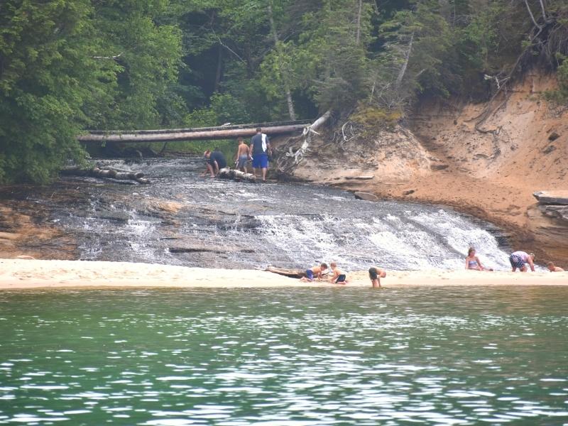 Families wade and play in the confluence where Chapel Beach Falls makes its last drop over rock ledges and flows into Lake Superior.