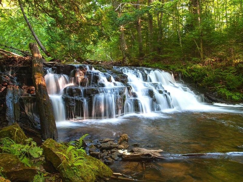 Mosquito Falls is a multi-tiered short drop waterfall in Pictured Rocks, surrounded by forest