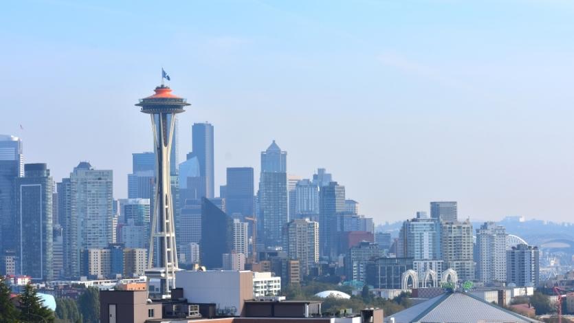 Skyline views of downtown Seattle with the orange roof of the Space Needle prominently featured as seen from Kerry Park on a clear but hazy day