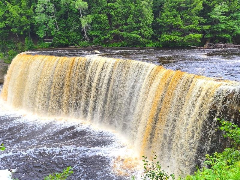 A mix of white and tan water cascades over a 50ft cliff at Upper Tahquamenon Falls in Michigan