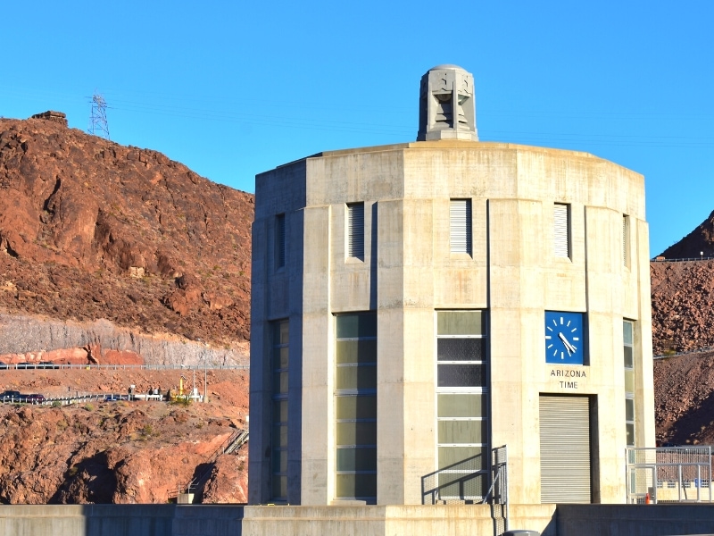 A conical intake tower on the Arizona side of the Hoover Dam features a blue clock that marks Mountain Standard Time for Arizona.