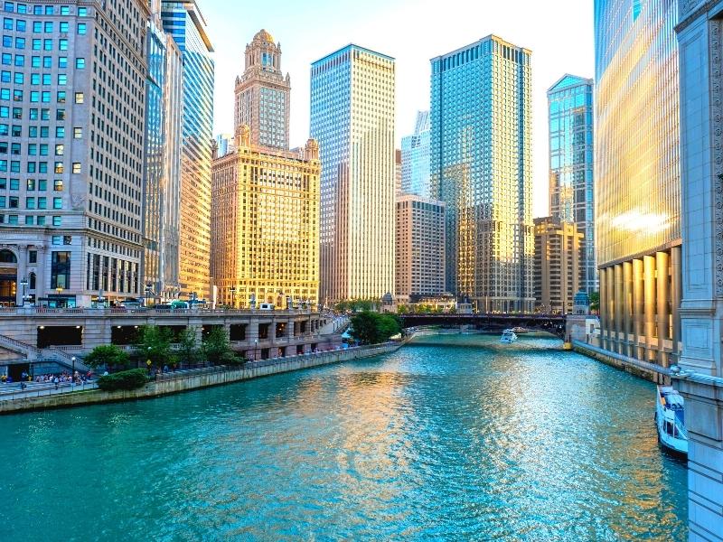 Chicago's skyscrapers glow blue and gold along the river as the sun sets