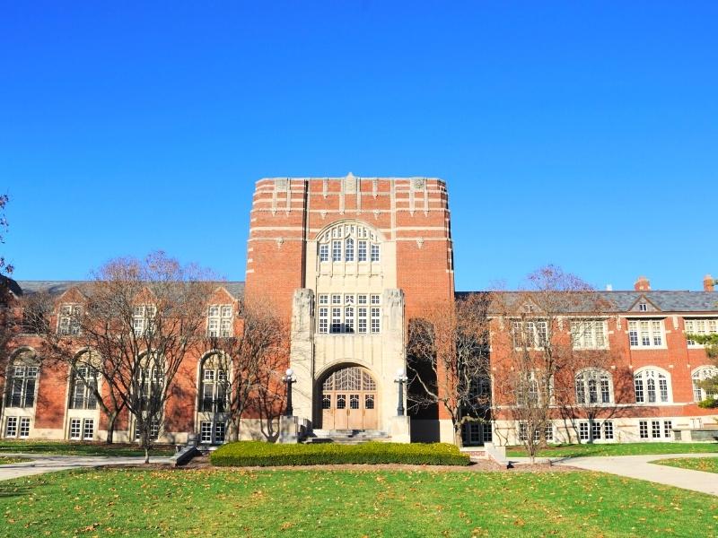 Tan brick and gray stone dominate the front facade of Purdue University's Student Union Building with green grass and a blue sky