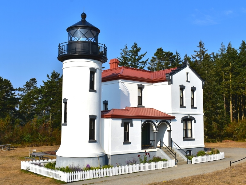 A two story white lightkeeper's house next to a 2 story lighthouse at Fort Casey on Whidbey Island
