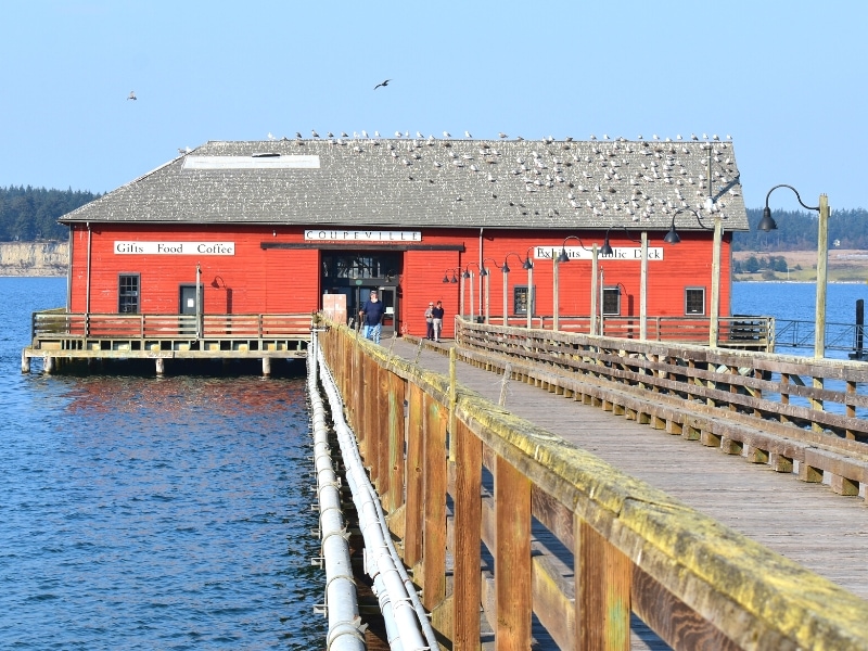 The Coupeville Wharf building is red on the water in Coupeville on Whidbey Island