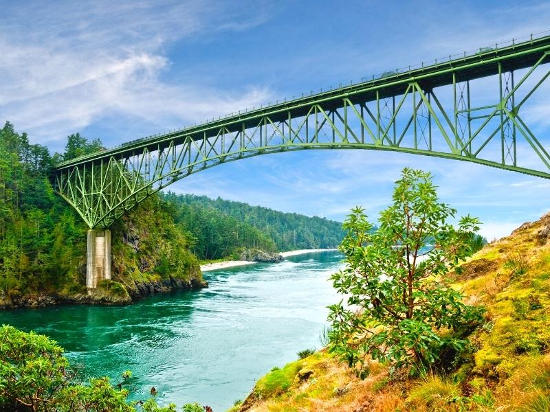 The steel truss Deception Pass Bridge connects mainland with Whidbey Island over the green waters below.