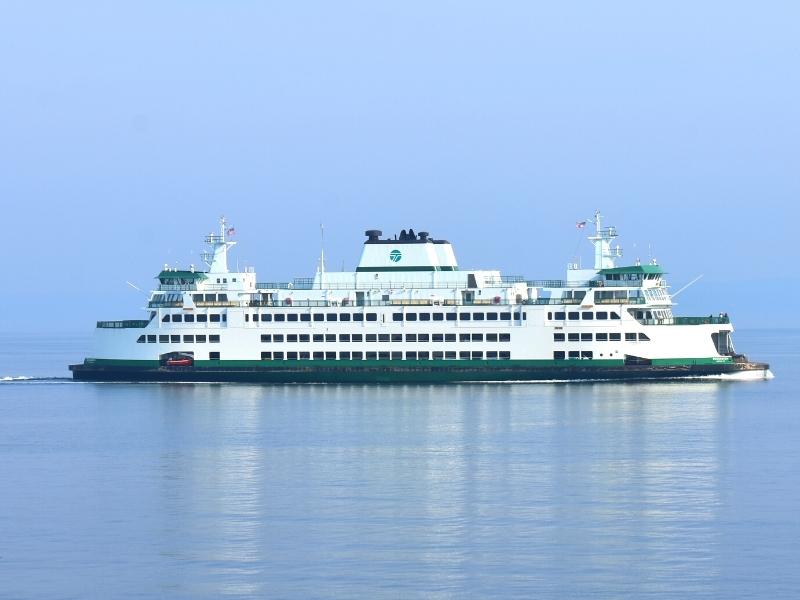 One of the green and white WSDOT-run Mukilteo-Clinton ferry ships cruises along the water on a foggy morning