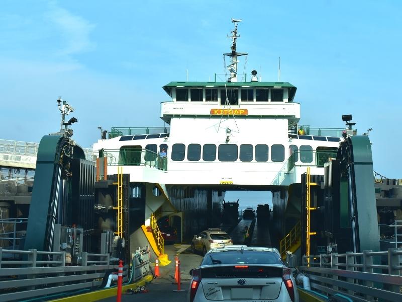 A ferry loads cars into the lower decks while pedestrians load via a gangway on the left