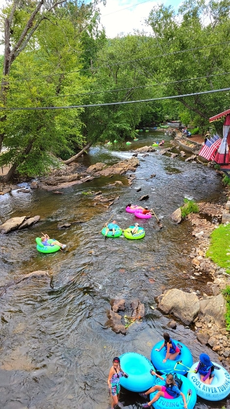 People in green, pink, and blue innertubes float down the Chattahoochee River in Helen, GA