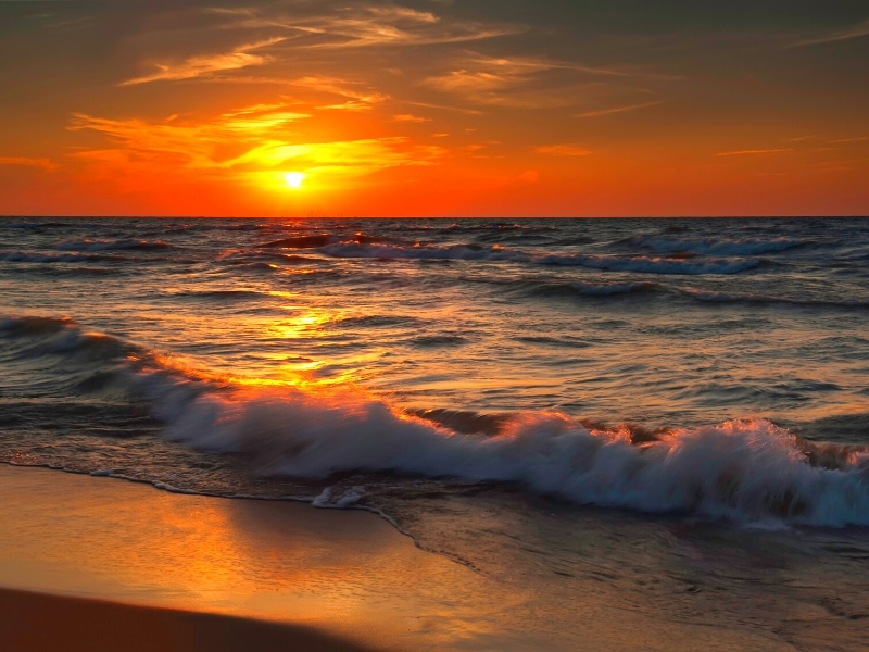 The sky glows orange and fades into black as the sun sets over Lake Michigan