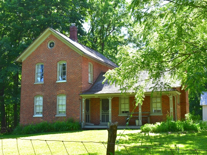 The Chellberg Farm historic brick farmhouse is surrounded by green trees and shades in Indiana Dunes National Park