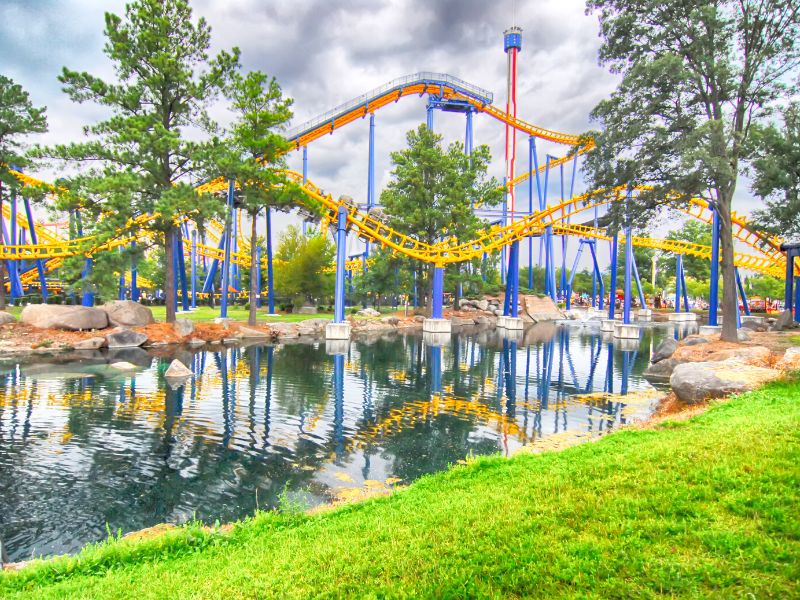 A rollercoaster winds back and forth over a water pond.