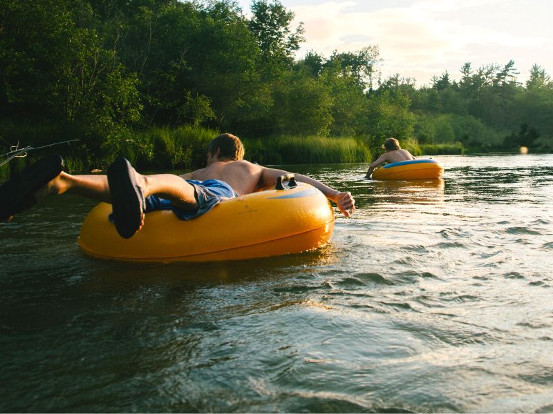 A guy lays on top of a yellow river tube, attempting to give his back some sun