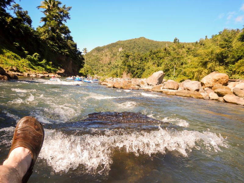 River tubers navigate a small rapids in a rocky boulder section of a river