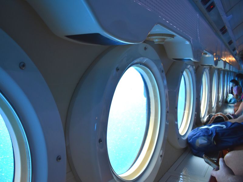 A photo view down the interior side of the Atlantis sub at all the portholes, with people looking out them