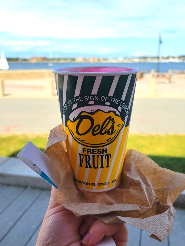 A hand holding out a Del's Lemonade cup in Newport, RI