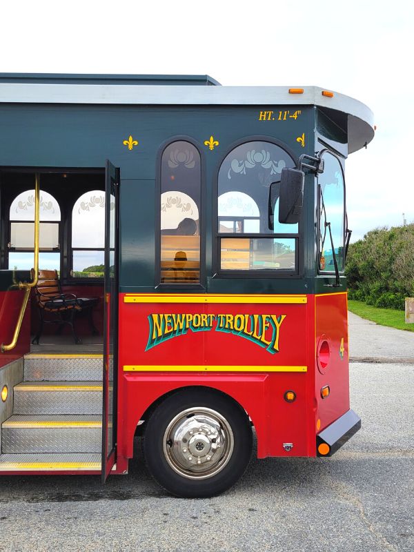 The red and dark green Newport trolley bus in a parking lot at Brenton Point, Newport, RI