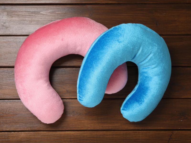 blue and pink horseshoe foam travel pillows on a wooden table