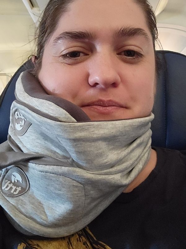 woman wearing a gray trtl brand travel pillow