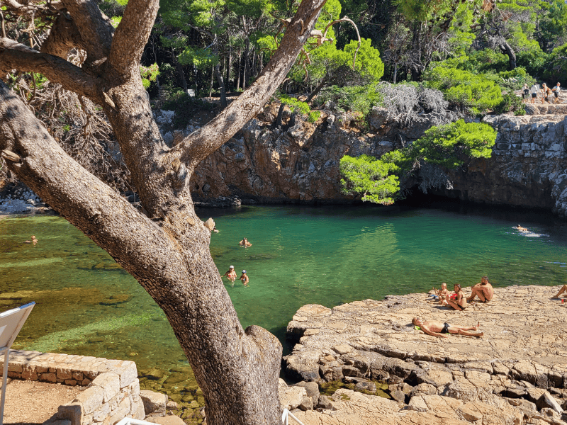 A shallow blue pool of water known as the Dead Sea or Mrtvo More surrounded by Lokrum Island's rocky landscape